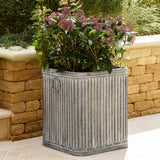 Decorative metal planter with a plant against a stone wall.