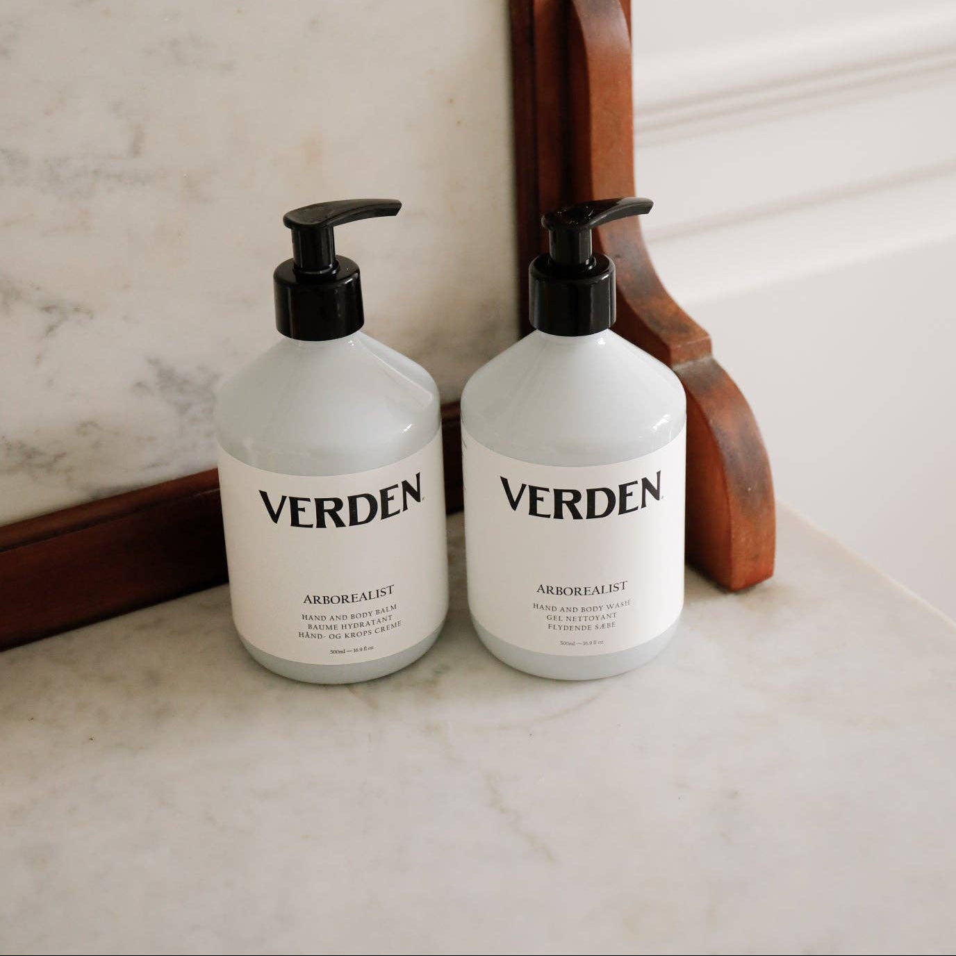Two 'VERDEN' bottles on a marble surface with a wooden frame in the background.