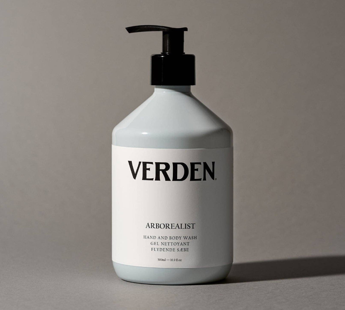 White bottle of Verden hand and body wash with a pump on a gray background