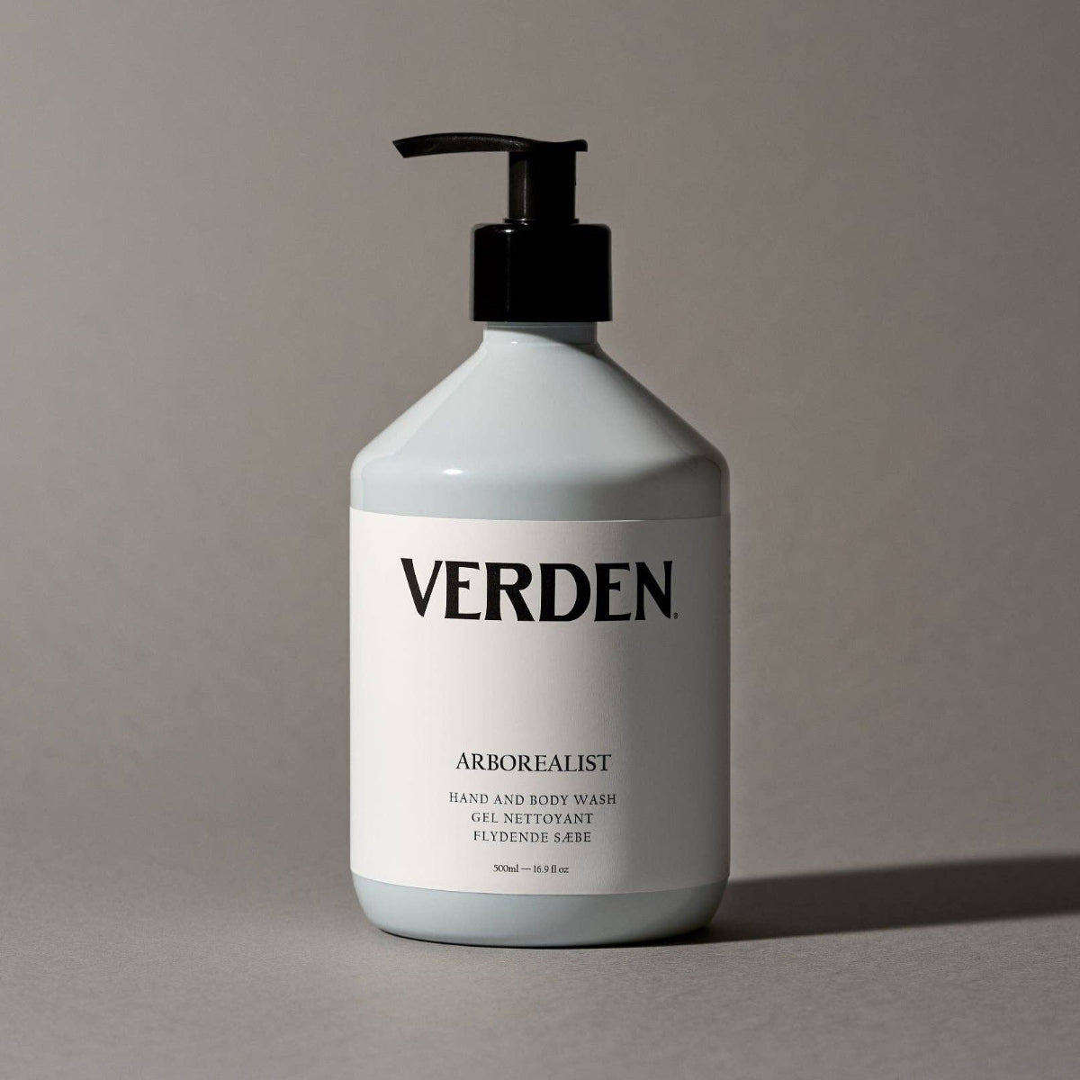 White bottle of Verden hand and body wash with a pump on a gray background