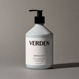 White bottle of Verden hand and body wash with a pump on a gray background