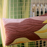 Colorful quilted cushion on a chair with a green curtain in the background