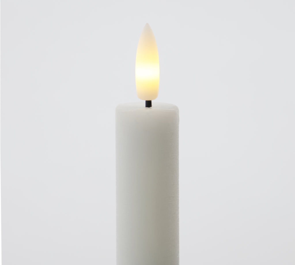 White candle with a lit LED wick on a light gray background