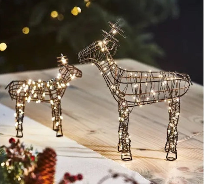Decorative wire reindeer with string lights on a snowy landscape