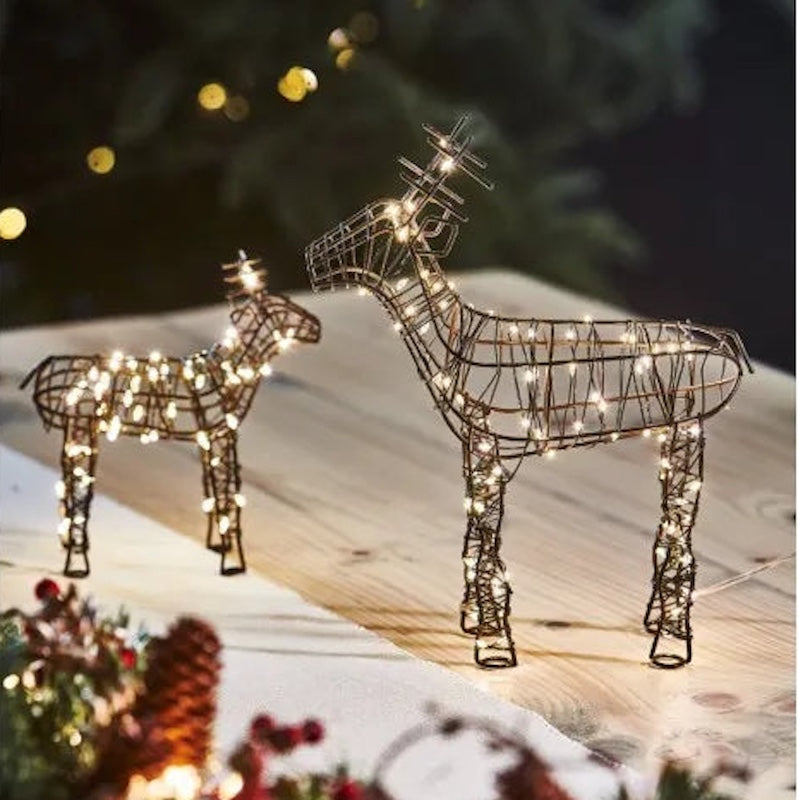 Decorative wire reindeer with string lights on a snowy landscape