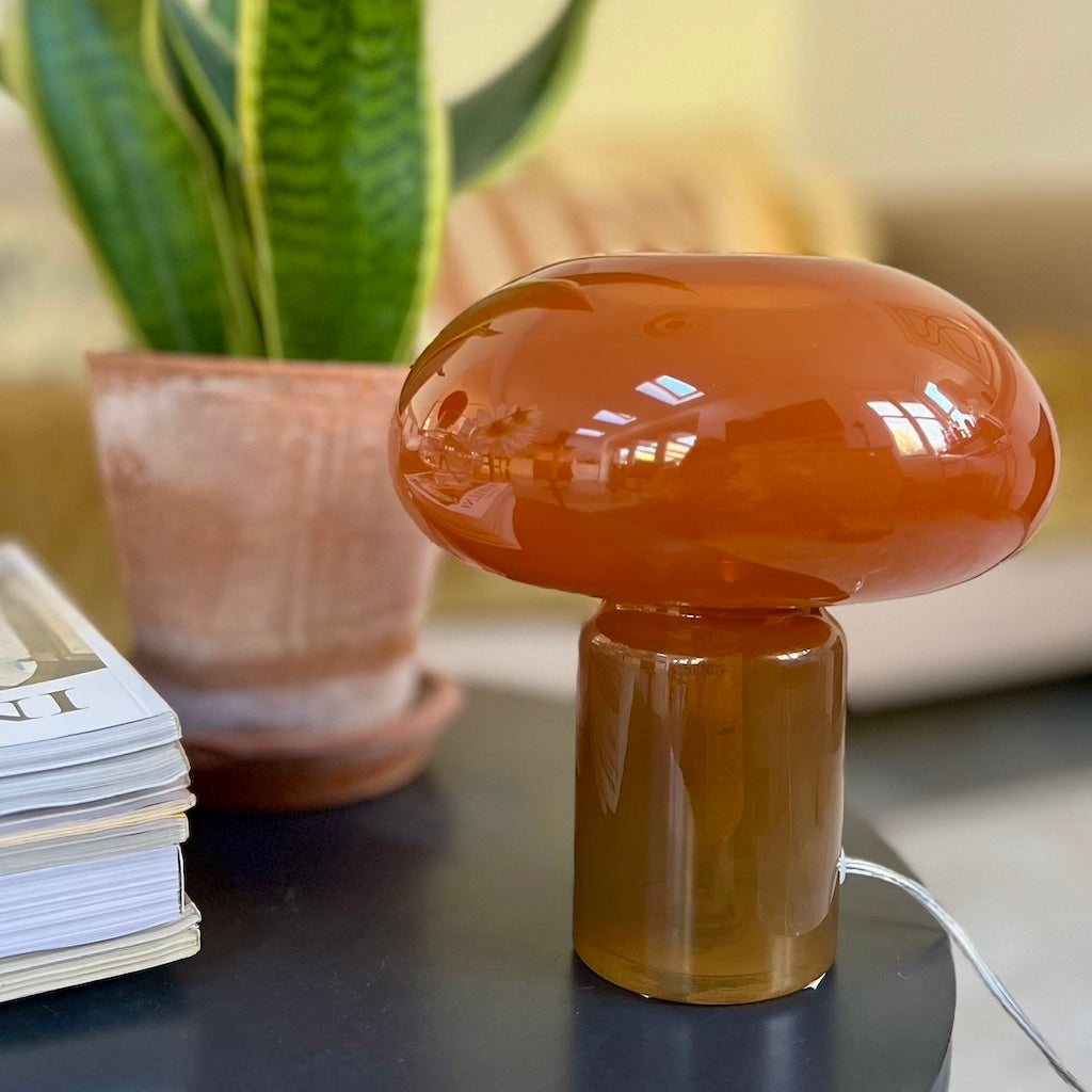 Orange Mushroom-shaped glass lamp on a table background