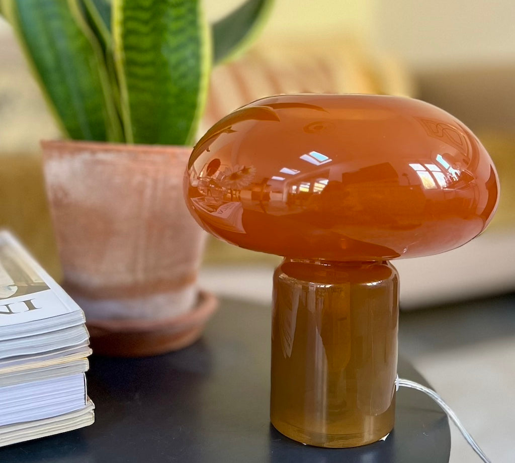 Orange Mushroom-shaped glass lamp on a table background