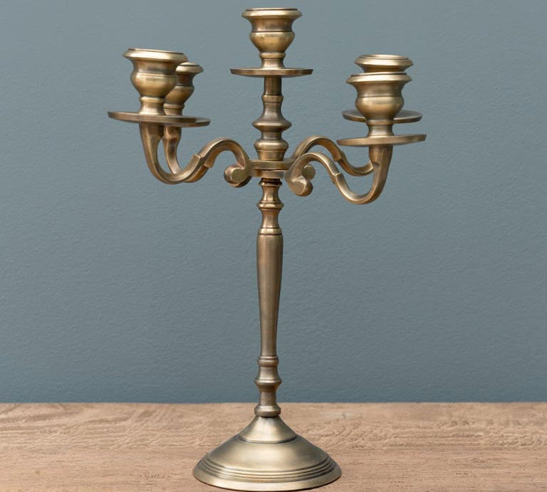 Bronze candelabra on a wooden surface with a gray background