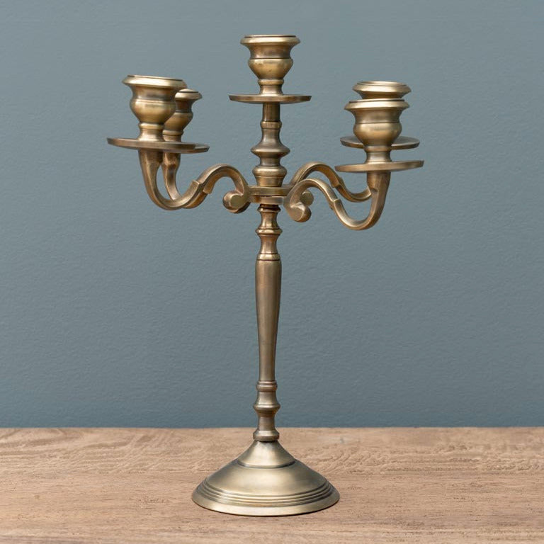 Bronze candelabra on a wooden surface with a gray background