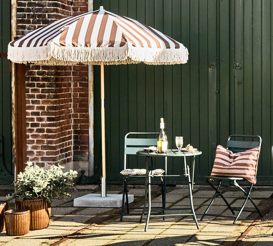 bistro table and chairs and striped umbrella
