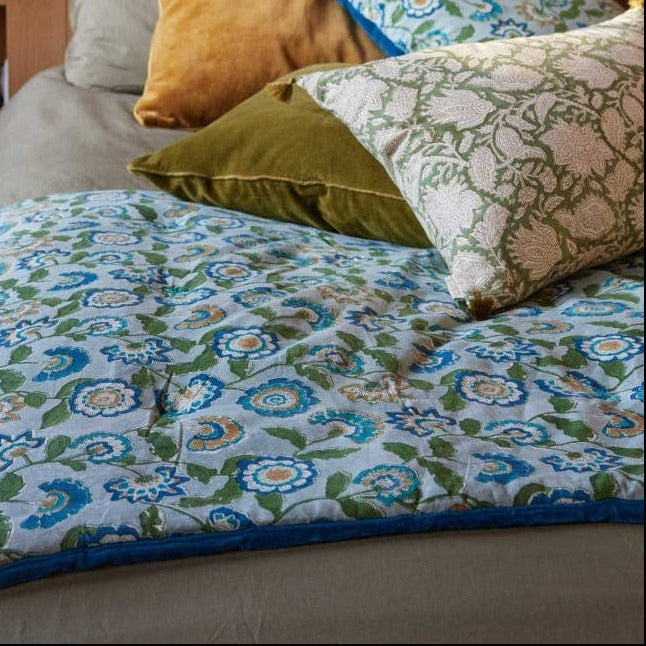 Bed with floral bedding and colorful pillows in a bedroom setting.