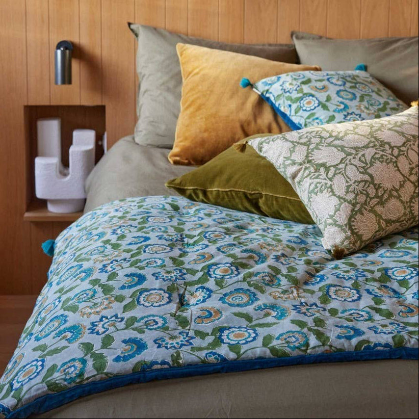 Bed with floral bedding and colorful pillows in a bedroom setting.