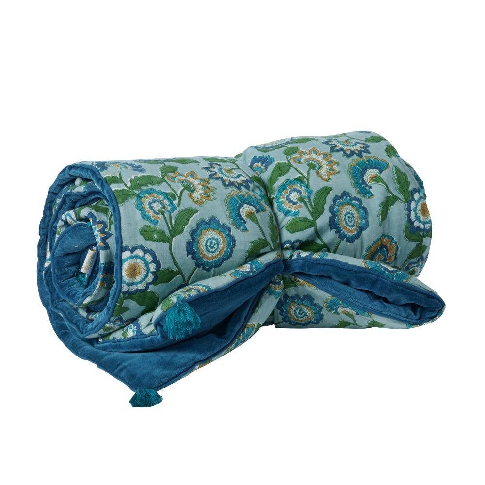 Rolled-up floral-patterned blanket with blue accents on a white background