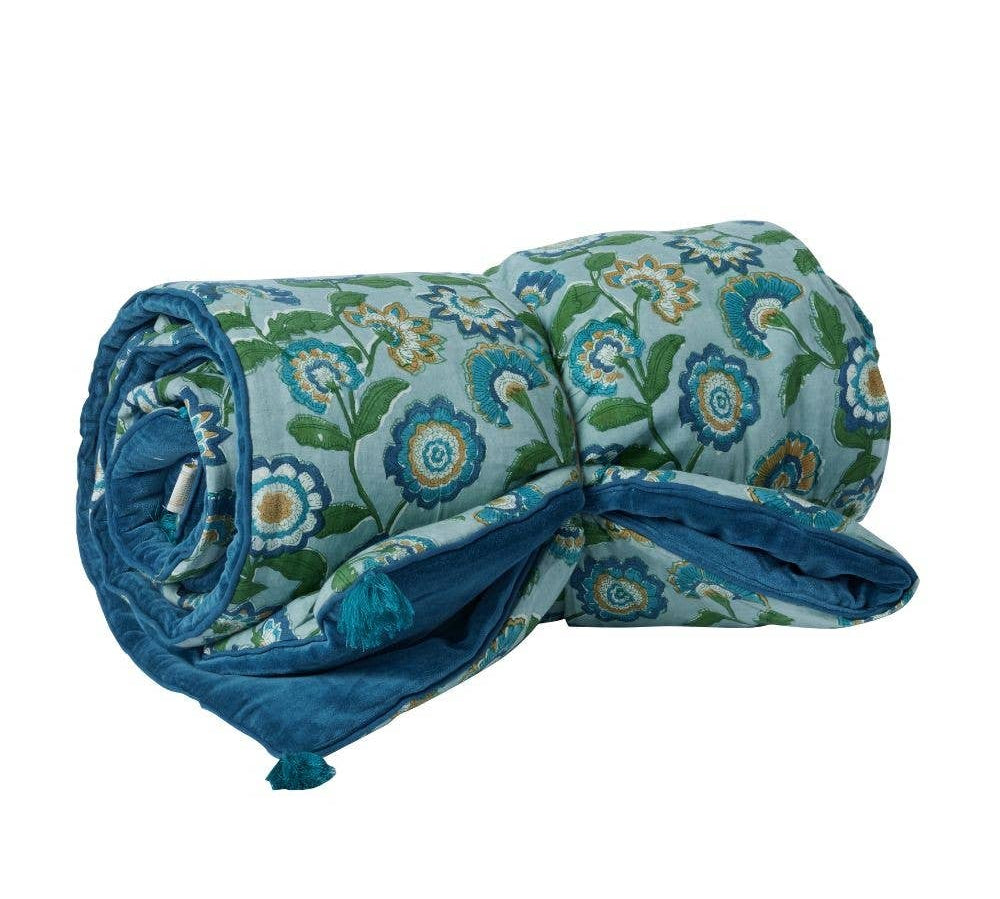 Rolled-up floral-patterned blanket with blue accents on a white background