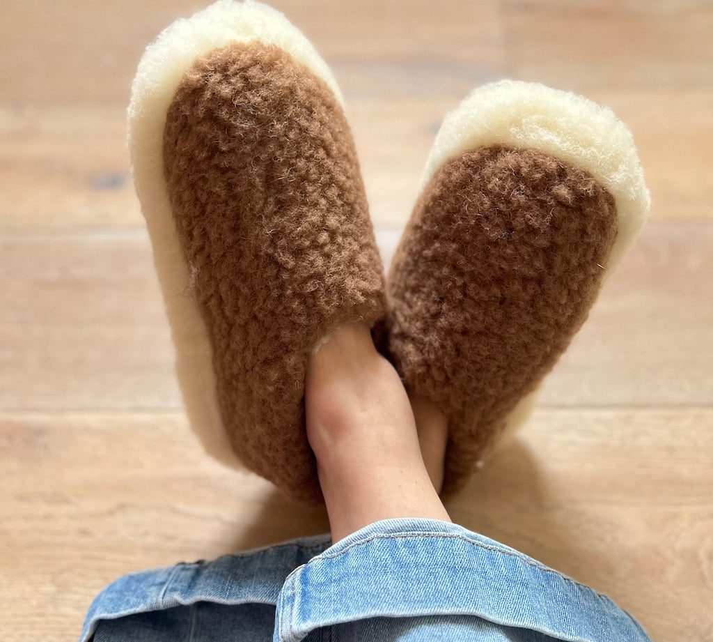 Brown fuzzy slippers worn indoors on a wooden floor.