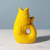 Yellow fish-shaped vase on a marble surface with a gray background
