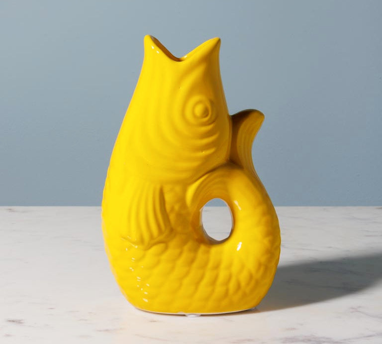 Yellow fish-shaped vase on a marble surface with a gray background