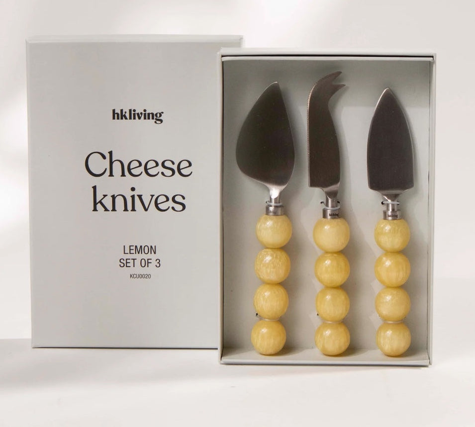 Set of three cheese knives with yellow handles in a box, branded 'hkliving'.