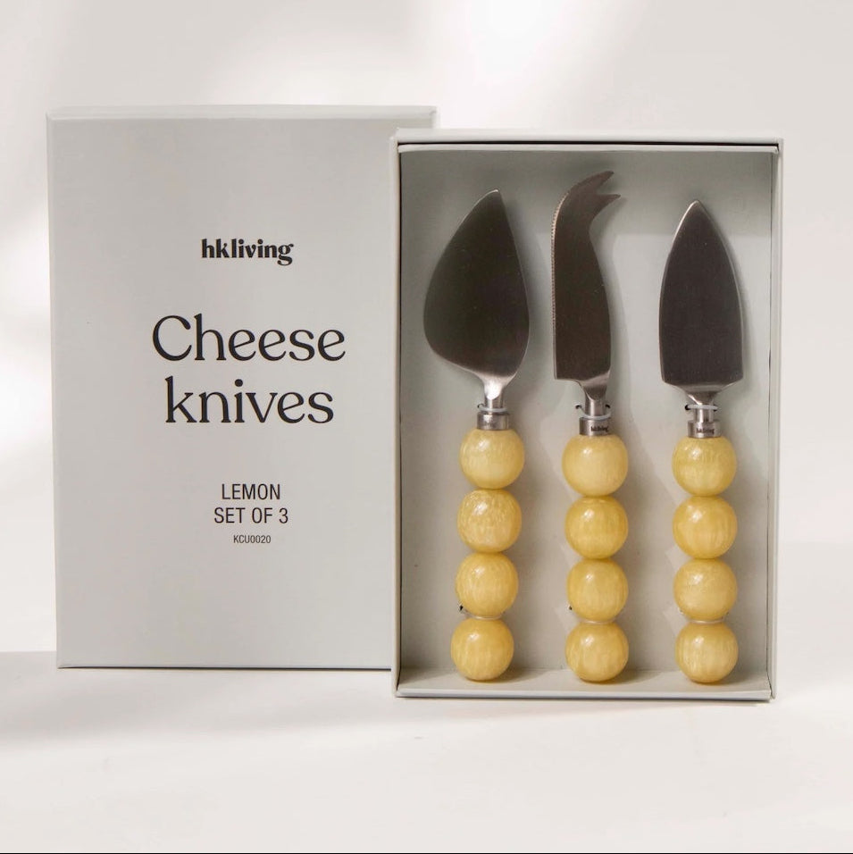 Set of three cheese knives with yellow handles in a box, branded 'hkliving'.