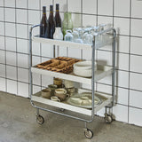 serving trolley with drinks and glasses against a tiled wall