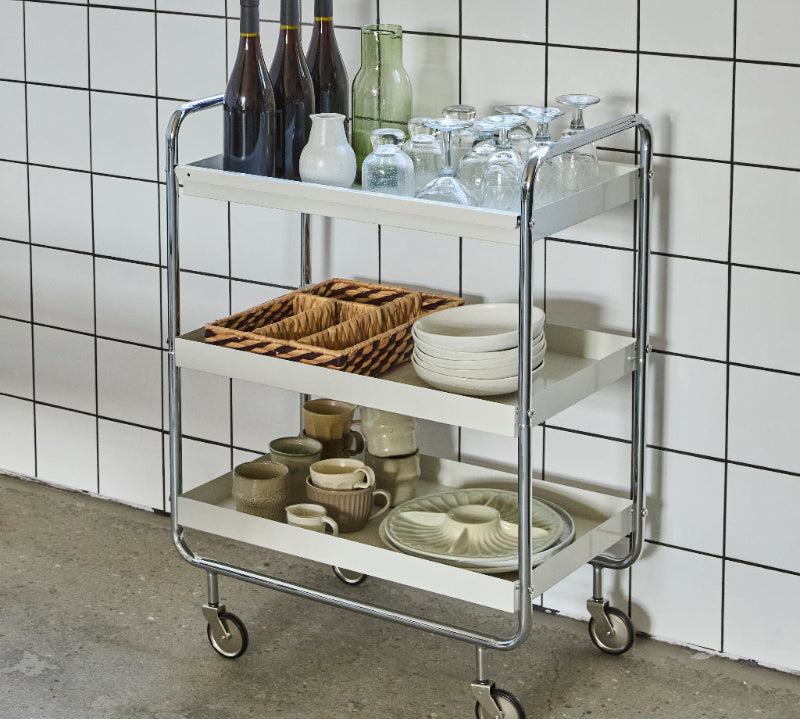 serving trolley with drinks and glasses against a tiled wall