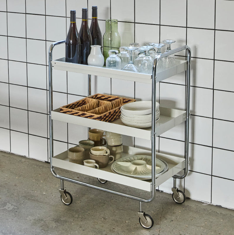serving trolley with drinks and glasses against a tiled wall