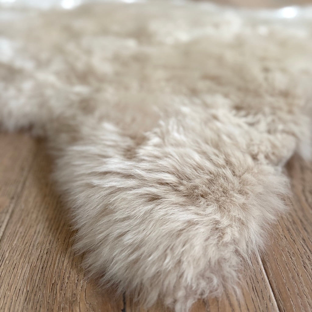 Close-up of a fluffy beige rug on a wooden floor