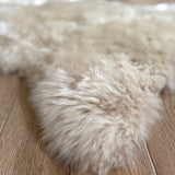 Close-up of a fluffy beige rug on a wooden floor