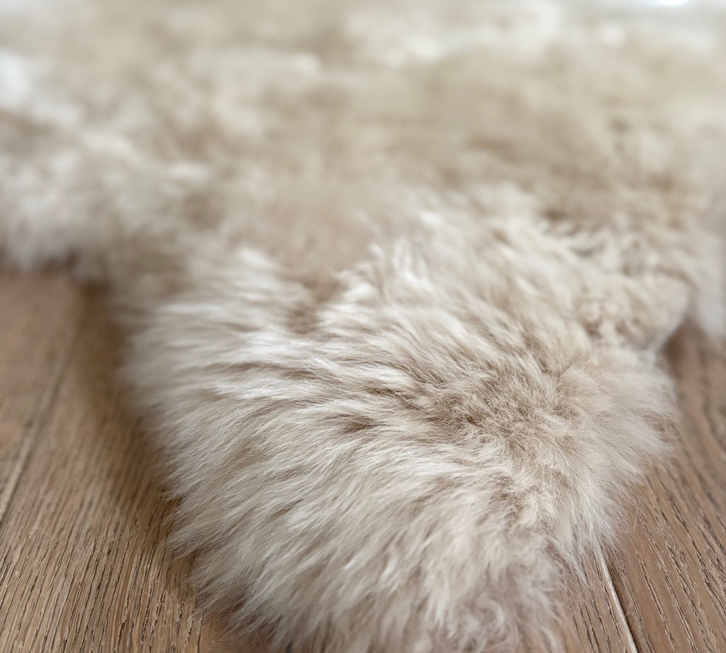 Close-up of a fluffy beige rug on a wooden floor