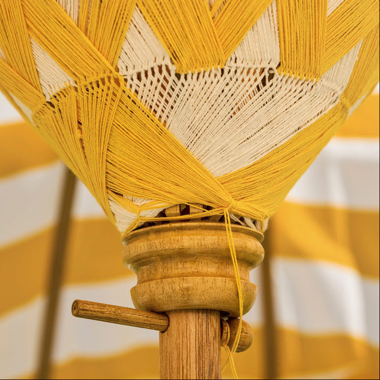 Close-up of a woven yellow and white umbrella with a blurred background