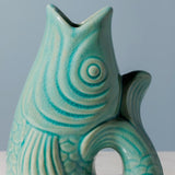Teal ceramic vase with wavy pattern on a gray background