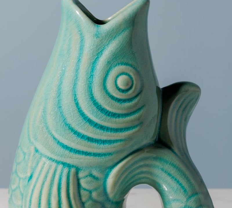 Teal ceramic vase with wavy pattern on a gray background