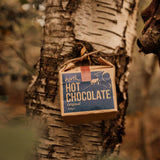 Box of hot chocolate hanging on a tree trunk in a forest setting