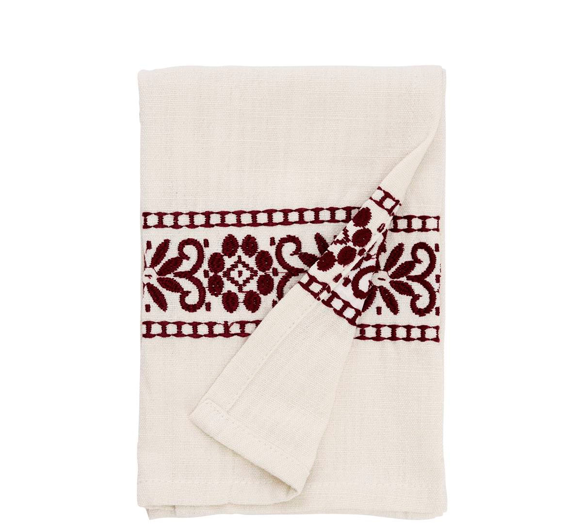 An off-white cotton muslin tea towel with a dark burgundy embroidered floral pattern, folded neatly on a solid white background.