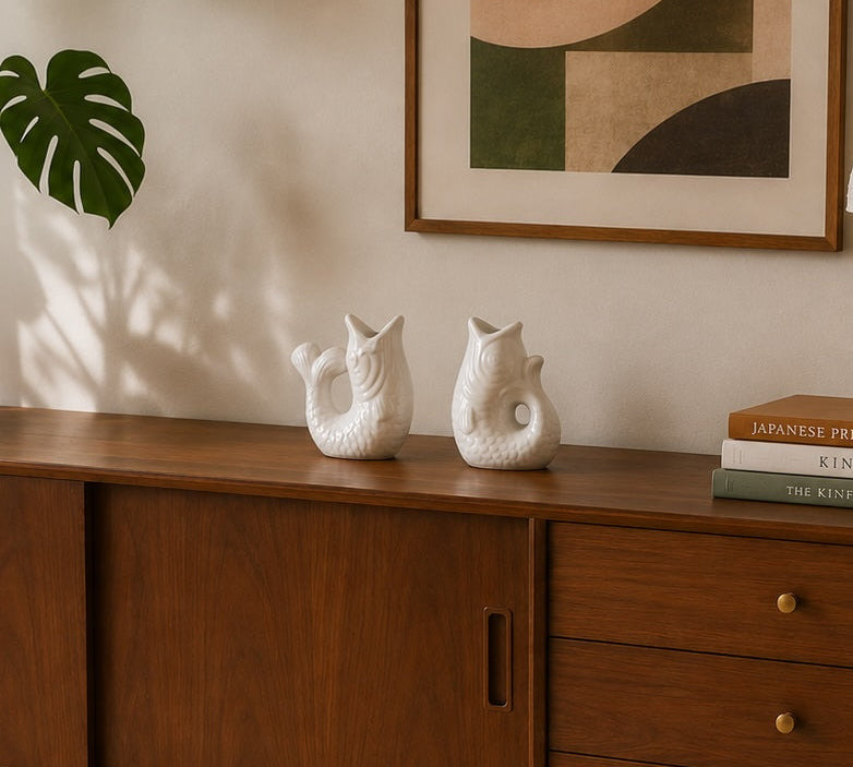 white ceramic fish shaped candle holders on a sideboard