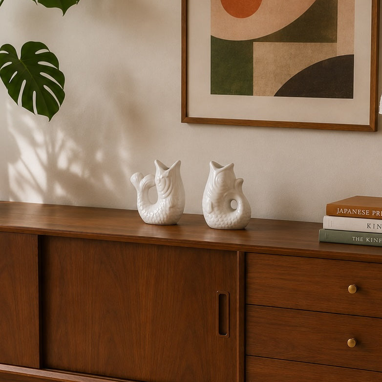 white ceramic fish shaped candle holders on a sideboard