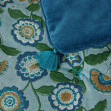 Blue sofa throw with tassel on a floral fabric background