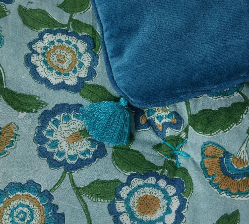 Blue sofa throw with tassel on a floral fabric background