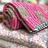 Stack of floral and patterned quilts on a wooden chair
