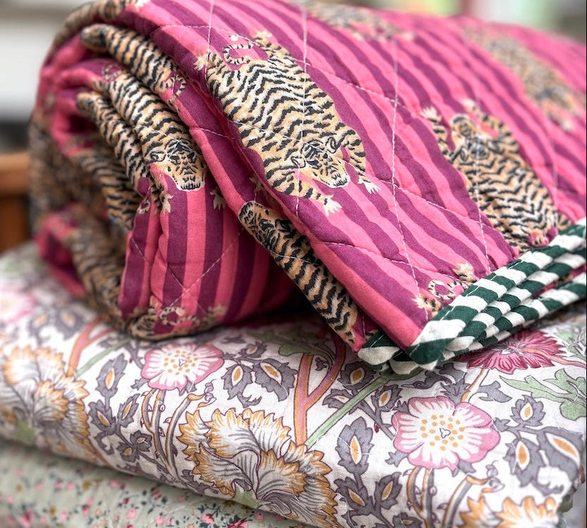 Stack of floral and patterned quilts on a wooden chair