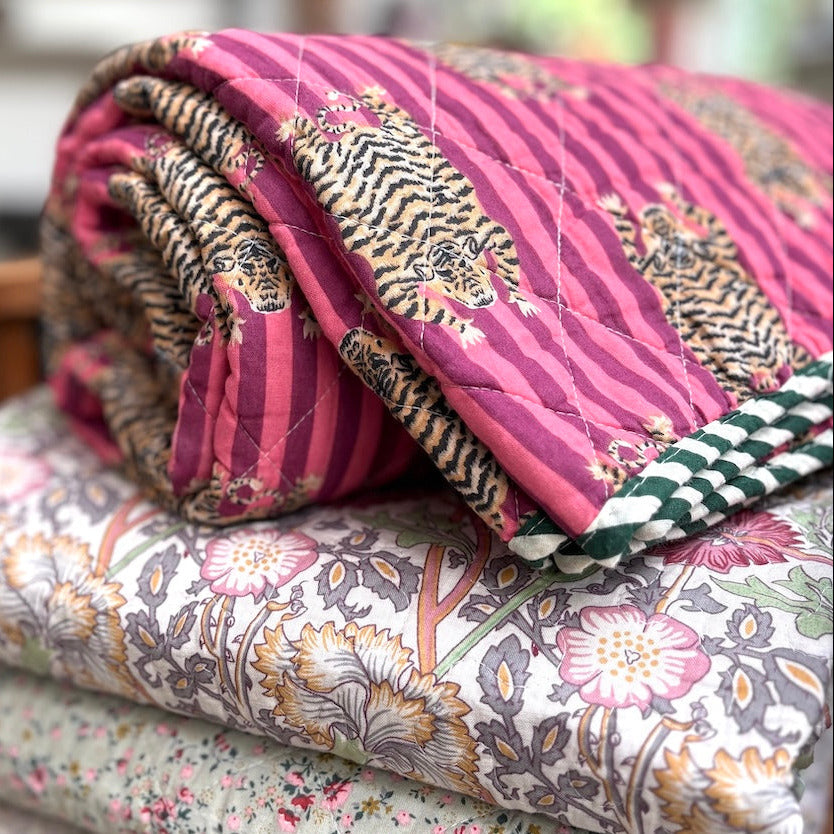 Stack of floral and patterned quilts on a wooden chair