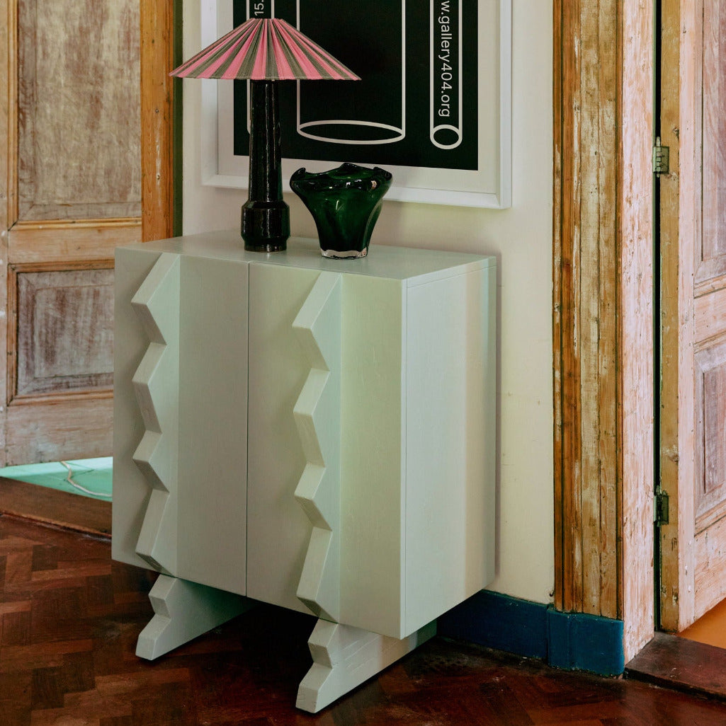 Decorative cabinet with a framed poster titled 'The Space Between' in a room with wooden doors.