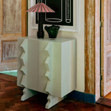 Decorative cabinet with a framed poster titled 'The Space Between' in a room with wooden doors.