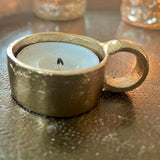 Gold candle holder with a candle on a reflective surface