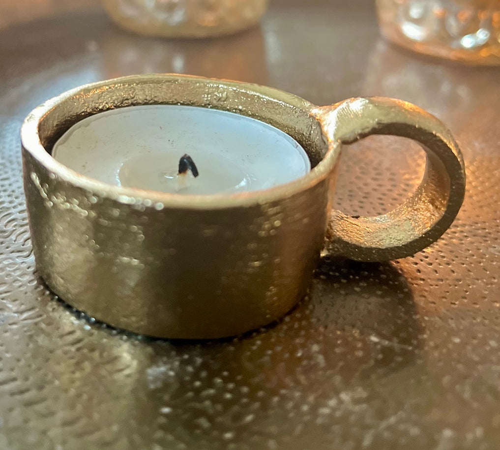 Gold candle holder with a candle on a reflective surface