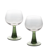Two clear stemmed wine glasses with ribbed green stems and circular green bases, photographed on a clean white background.