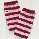 A pair of hand-knit hand warmers featuring horizontal stripes of deep burgundy and light pink, displayed on a white wooden background.