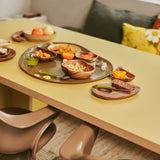 Dining table with food platters and chairs in a cozy room.