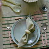 Dining table setting with plates, cutlery, and a bowl of nuts on a patterned tablecloth.