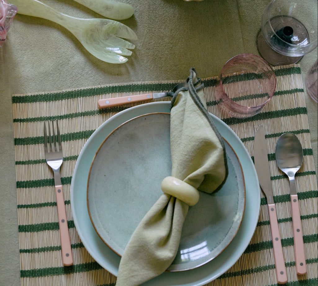 Dining table setting with plates, cutlery, and a bowl of nuts on a patterned tablecloth.